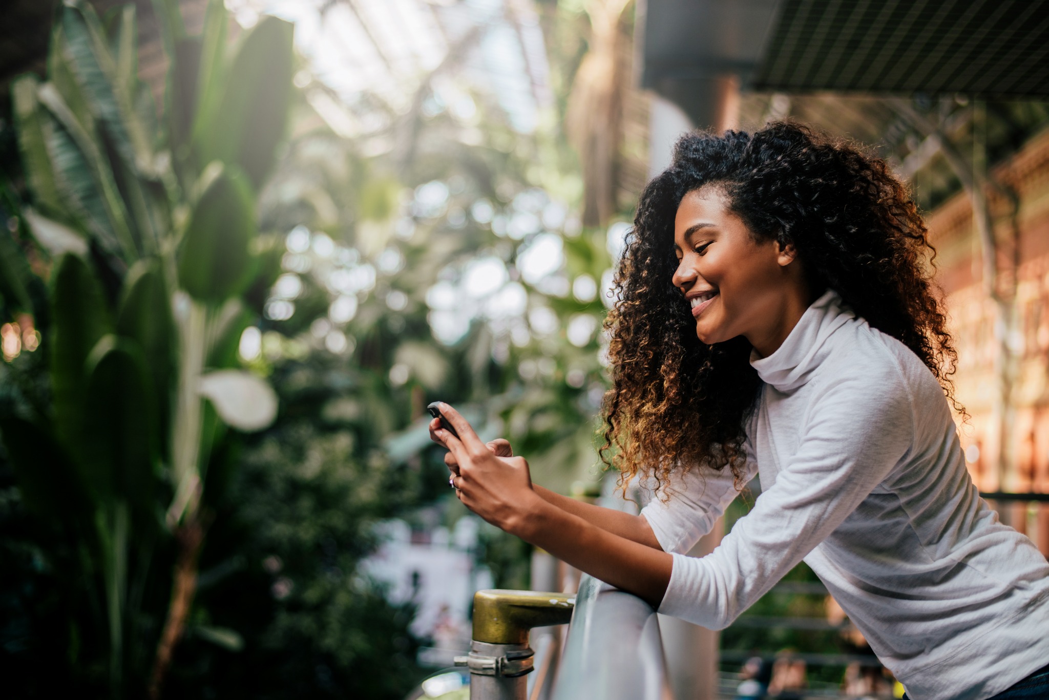 A woman smiling at her phone in a garden café